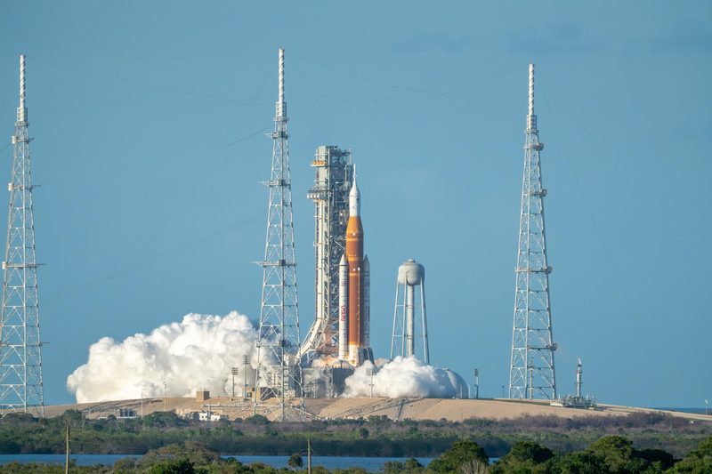 The SLS rocket lifting off from its launch pad with clouds of exhaust