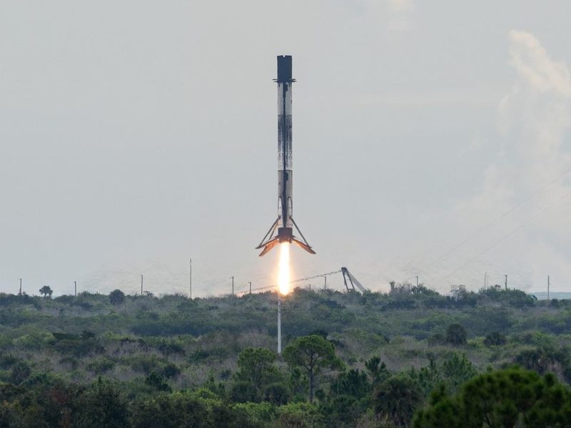 A Falcon 9 booster descending on its engine flame toward the landing zone