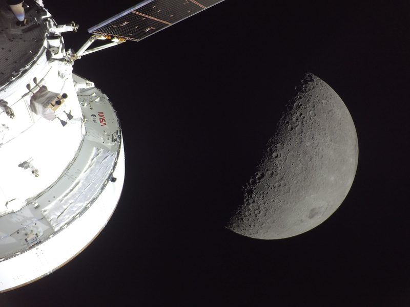 NASA's Orion spacecraft lit by the Sun, with a half-lit Moon behind it, during the Artemis II flight in April 2026